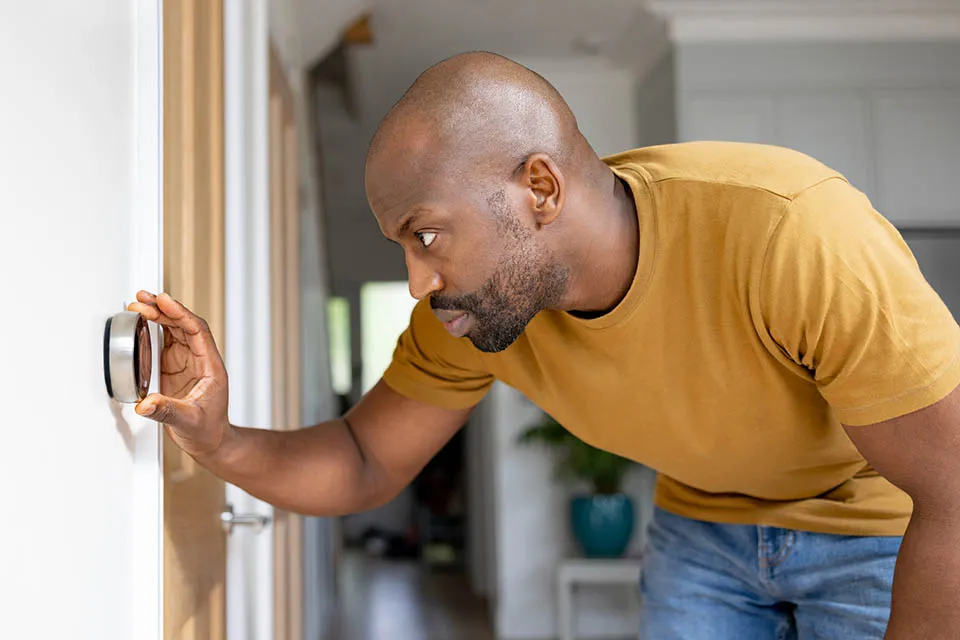Man adjusting the temperature on the thermostat