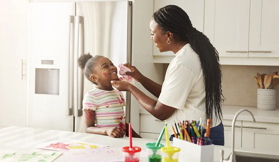 mother wiping paint off of her daughters face